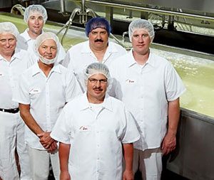 Six men next to a cheese vat