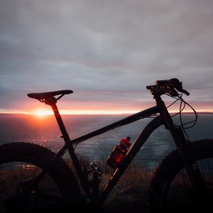 black and red hardtail mountain bike near body of water during sunset